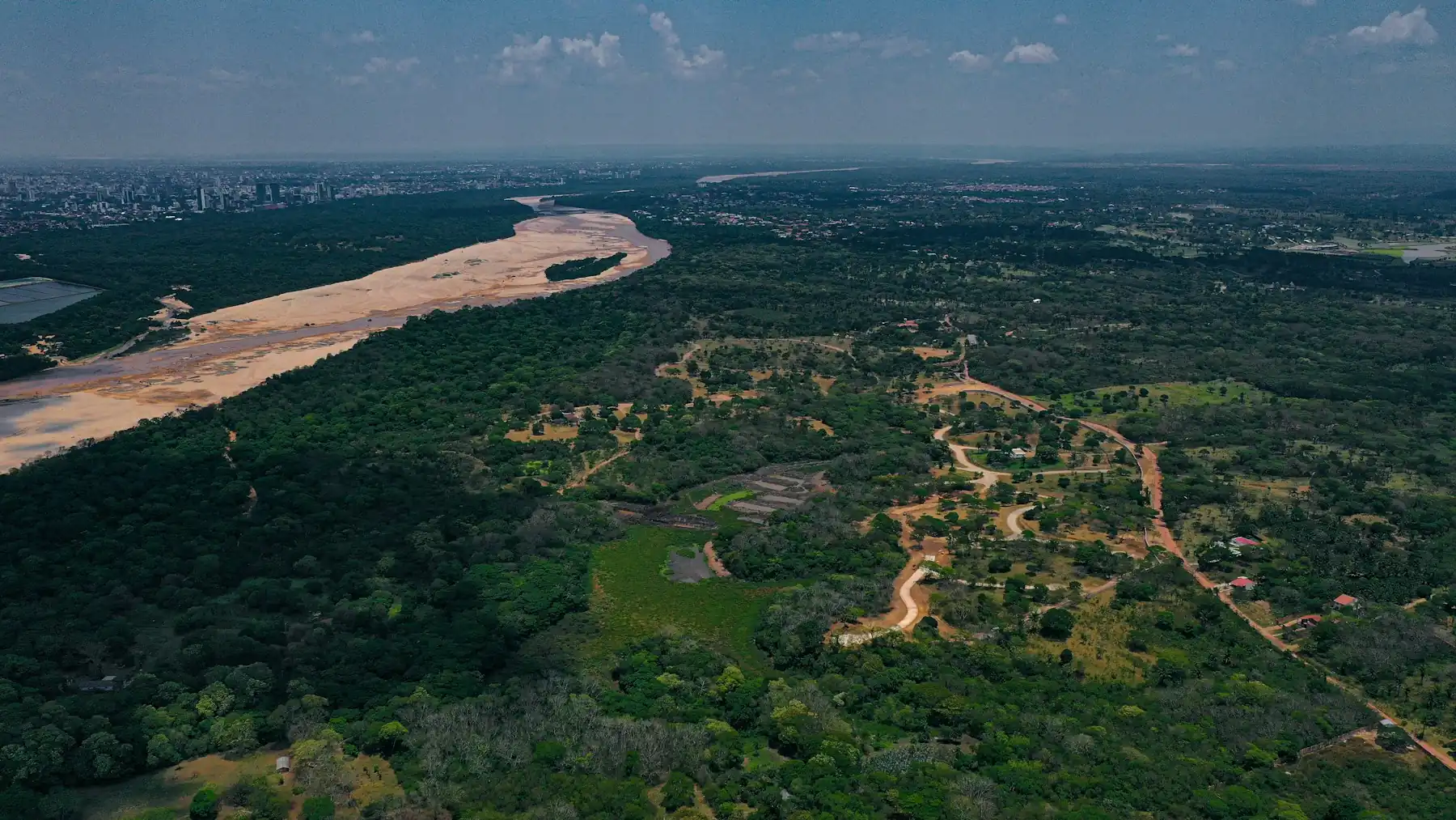 Vista aérea de um rio largo correndo entre morros cobertos de floresta